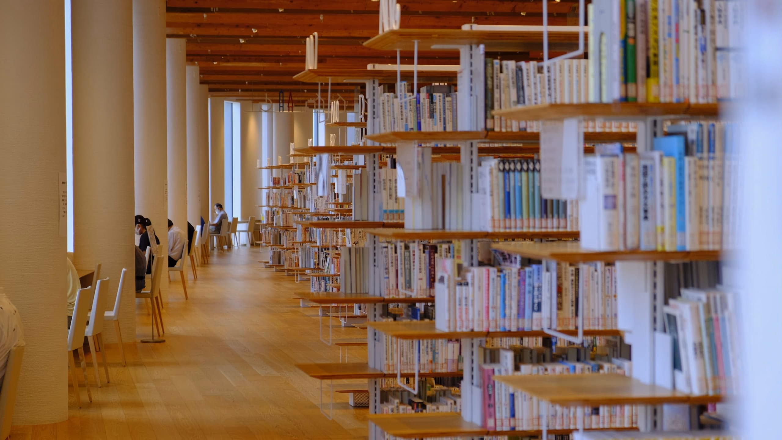 富山県立図書館内部の写真。木製の床と天井、整然と並ぶ本棚。